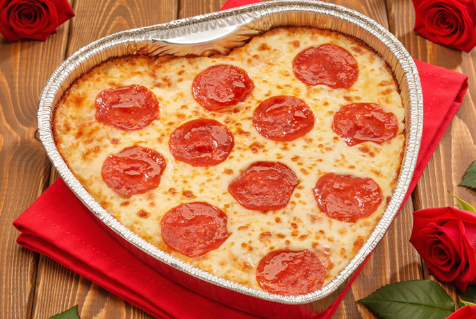 Heart-shaped pepperoni pizza surrounded by roses