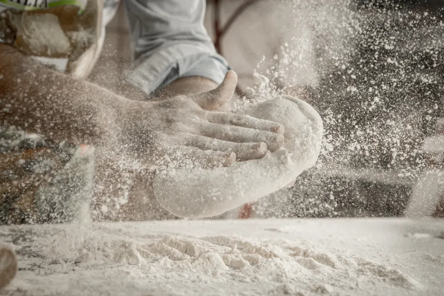 A pizza maker tossing pizza dough