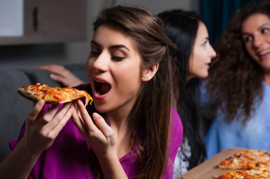 woman-eating-pizza.jpg Women eating Hungry Howie's pizza during movie night